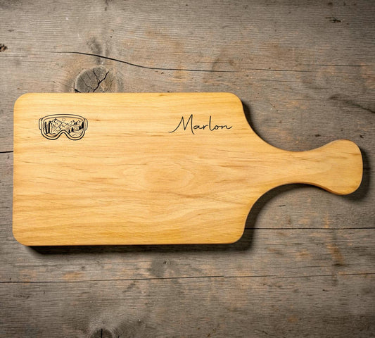 Schwarzwald Gravur alder wood cutting board with handle, personalized with name Marlon and ski goggles engraving.